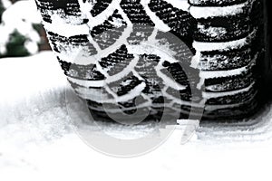 The car tire in the snow close up. Car tracks on the snow. Traces of the car in the snow. Winter tires. Tyres covered with snow at