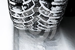 The car tire in the snow close up. Car tracks on the snow. Traces of the car in the snow. Winter tires. Tyres covered with snow at