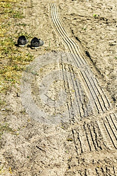 Car tire track in the sand and old shoes in Germany