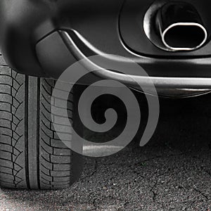 Car tires close-up. Car wheel and exhaust pipe