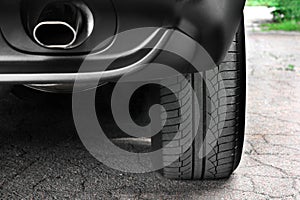 Car tires close-up. Car wheel and exhaust pipe