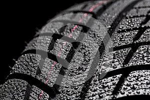 Car tires close-up Winter wheel profile structure with waterdrops on blue black background