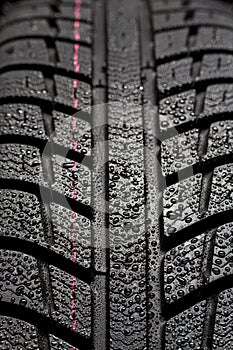 Car tires close-up Winter wheel profile structure with waterdrops on blue black background