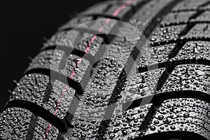 Car tires close-up Winter wheel profile structure with waterdrops on blue black background