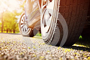 Car tires closeup on asphalt road on summer day at park