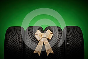 Car tires, new tyres, winter wheels isolated on green background with bow ribbon present