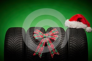 Car tires, new tyres, winter wheels isolated on green background with bow ribbon present