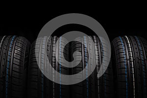 Car tires stacked in a row isolated on black background, closeup. photo