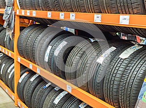 Car tires stacked in rows on shelves or rack in auto store. Variety of car\'s tyres on shelf with prices at store