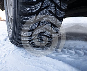 Car tires on winter road covered with snow, Closeup