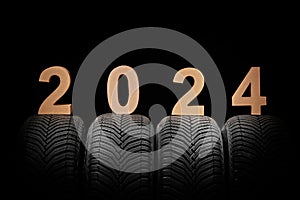 Car tires, winter wheels and text new year 2024 isolated on black background