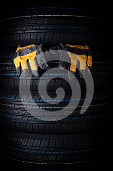 Car tires and yellow mechanic gloves on a black background. Tires with rubber gloves.