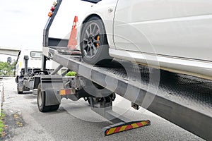 Car towed onto flatbed tow truck with hook and chain