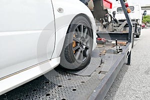 Car towed onto flatbed tow truck with hook and chain
