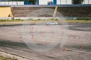 Car and traffic cones, driving school concept. Training car performs exercises on training ground in the driving school. Stadium