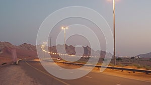 car traffic on highway in desert in evening time, empty road and wind