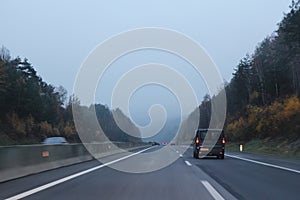 Car traffic on higway with fog and autumn forest on sides