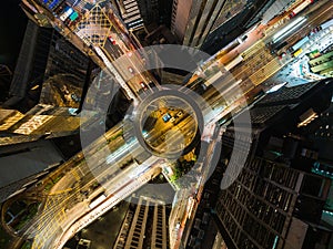 Car traffic on road junction intersection in Hong Kong city downtown at night. Drone aerial top view