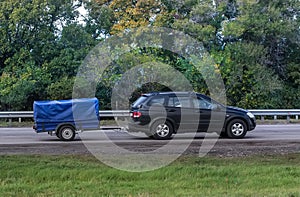 car with the trailer goes on highway