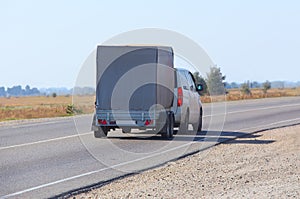 car with the trailer goes on highway