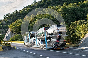 Car Transporter carrying. injured cars transported on the car platform on a mountain road. truck carrying cars