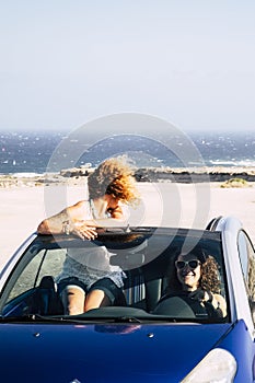 Car travel friends transportation two happy woman ejoy convertible auto together in summer trip holiday vacation - ocean and beach