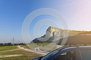 Car for travel with a roof rack on a mountain road, against the backdrop of the White Rock