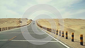 Car traveling on highway that runs through gobi desert