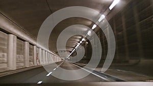 Car travels through night city streets and tunnel