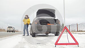 Car trouble. An emergency sign. Car trouble on a snowy country road. A young woman call the rescue service