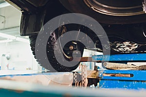 Car on two-post elevator in workshop service station.