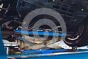 Car on two-post elevator in workshop service station.