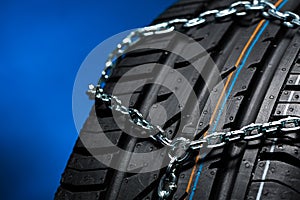Car tyre with snow chain in the winter with blue background
