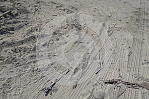 Car Tyre Tracks On The Beach Sand In Perspective. Car Tire Prints On A Road Leading To Beach Covered In Sand. Wheel Tracks On The