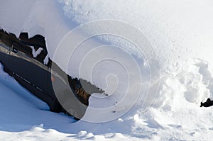 Car under snowdrift in city yard after heavy snowfall