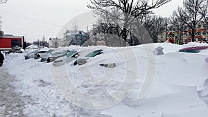 Car under thick blanket of snow after storm. Vehicles buried under ice.