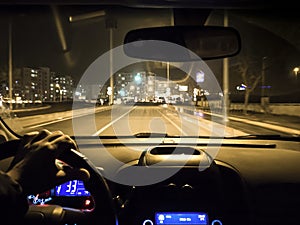 Car use on night road. man holding steering wheel in car