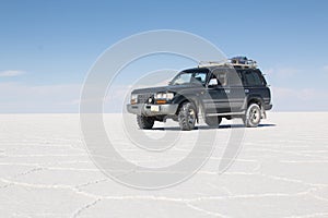 Car on the Uyuni Salar in Bolivia. Blue Sky and white salt background