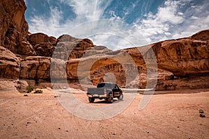 A car in view through a rock arch in the desert of Wadi Rum