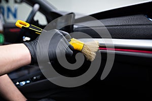 Car wash or car detailing studio worker carefully cleaning car interior