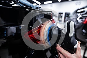 car wash or car detailing studio worker polishes the paintwork