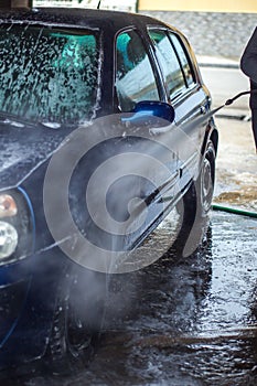 Car Wash Closeup. Washing Car by High Pressure Water