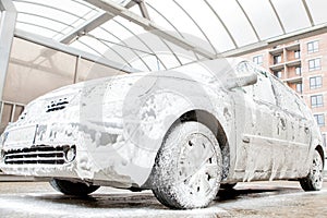 Car wash with foam in car wash station. Carwash. Washing machine at the station. Car washing concept. Car in foam