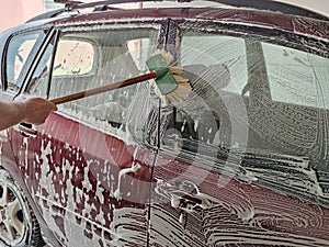 Car wash, foam-drenched car is wiped with a brush