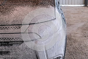 Car wash with Karcher. A man applies shampoo to a black car photo