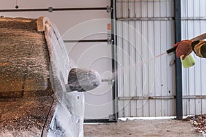 Car wash with Karcher. A man applies shampoo to a black car