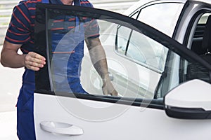 Car wash in overalls opened the door of a white car for cleaning inside