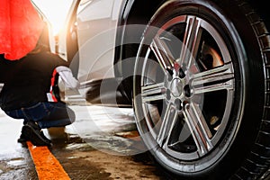 Car wash service, cleaning tires and wheels with cleaning soap foam and high-pressure water, polishing alloy wheels and tires