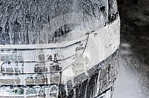 Car wash with soap. Black car covered by foam.