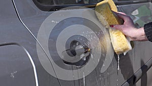 Car wash. A woman washes the body of a car with a sponge